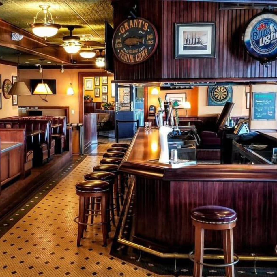 Interior of GS Steamers Bar & Grill, featuring a long wooden bar with stools and booth seating.