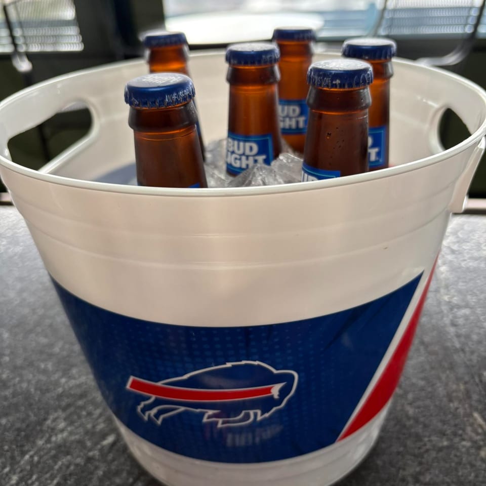 A white bucket with a Buffalo Bills logo holds six Bud Light bottles on ice.