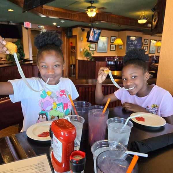 Two young girls happily stretching cheese from mozzarella sticks at GS Steamers Bar & Grill.