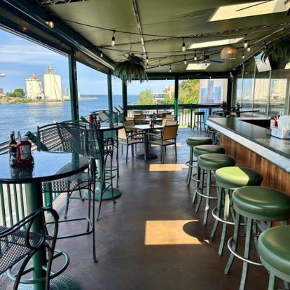GS Steamers Bar & Grill's outdoor patio with tables, bar stools, and a waterfront view.