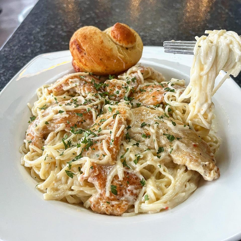 Creamy pasta with chicken, parmesan, and parsley, served with a bread roll, at GS Steamers Bar & Grill.